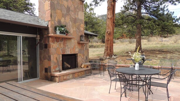 Un patio al aire libre con suelo de piedra, chimenea de piedra y mobiliario de metal.