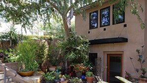 A courtyard with a stone staircase, potted plants, and a building with a door and windows. - Ocean & Lagoon View Studio, Walk to Beach, Large Private View Deck  (Del Mar)