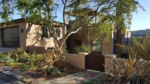 A modern house with a stone pathway, a wooden gate, and a variety of plants. - Ocean & Lagoon View Studio, Walk to Beach, Large Private View Deck  (Del Mar)