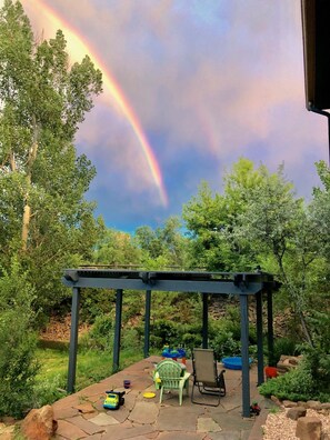 A covered patio area with a stone floor, a pergola, and outdoor furniture including a chair and a table. - One of the nicest house rentals available in Lyons, Colorado (Lyons)
