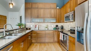 A modern kitchen with wooden cabinets, stainless steel appliances, and a stone backsplash. - One of the nicest house rentals available in Lyons, Colorado (Lyons)