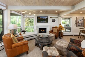 A spacious living room with a fireplace, leather sofas, a round coffee table, and a view of the outdoors. - Top of the Village Leaf 502~Ski-in/out~HT~Pool~Grill~Parking (Snowmass Village)