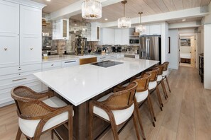 A spacious kitchen with a large island, white cabinetry, and a modern chandelier. - Top of the Village Leaf 502~Ski-in/out~HT~Pool~Grill~Parking (Snowmass Village)