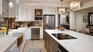 A modern kitchen with white cabinetry, stainless steel appliances, and a marble island. - Top of the Village Leaf 502~Ski-in/out~HT~Pool~Grill~Parking (Snowmass Village)