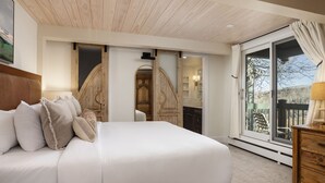 A bedroom with a large bed, wooden headboard, and a sliding glass door leading to a balcony. - Top of the Village Leaf 502~Ski-in/out~HT~Pool~Grill~Parking (Snowmass Village)