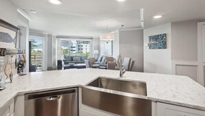 Una cocina moderna con lavavajillas integrado, un lavamanos de acero inoxidable y un comedor con mesa y sillas.