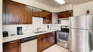 Una cocina moderna con gabinetes de madera, electrodomésticos de acero inoxidable, lavavajillas y microondas.