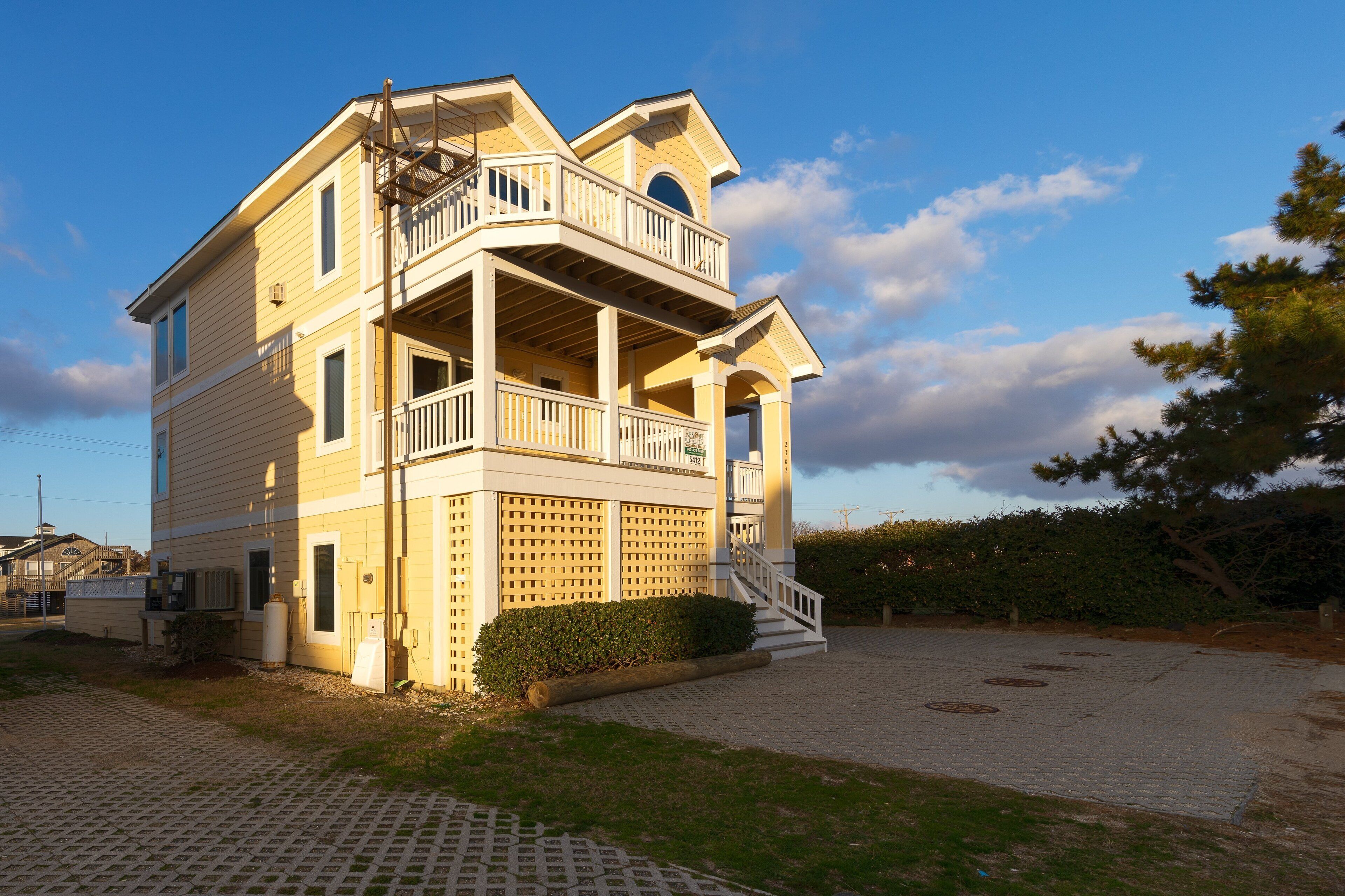 A multi-story building with a balcony, a staircase, and a paved driveway.