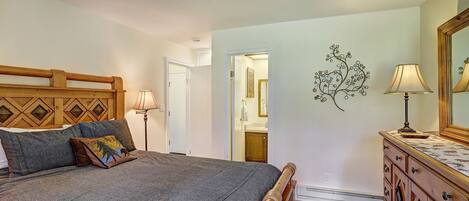 A bedroom with a bed, dresser, and a wall-mounted lamp.