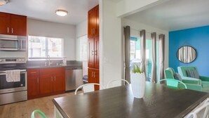 Uma cozinha moderna com armários de madeira, eletrodomésticos de aço inoxidável e uma área de jantar com mesa e cadeiras.