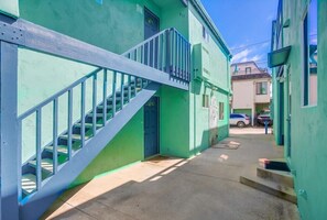 A narrow alleyway with a blue staircase leading to a green building.