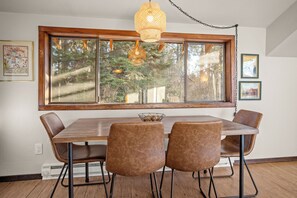Enjoy meals with a view of the surrounding forest from this dining area, featuring a wooden table and four unique chairs.