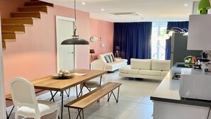 A modern living room with a dining area, a staircase, a kitchen, and a view of the outdoors. - Walking distance to the beach, bars & restaurants. 3 bed/3 bath condo with pool! (Noord)