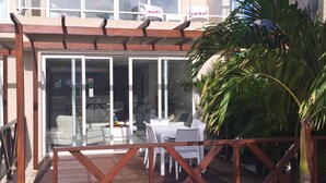 A modern building with a covered patio area, outdoor seating, and a palm tree. - Walking distance to the beach, bars & restaurants. 3 bed/3 bath condo with pool! (Noord)