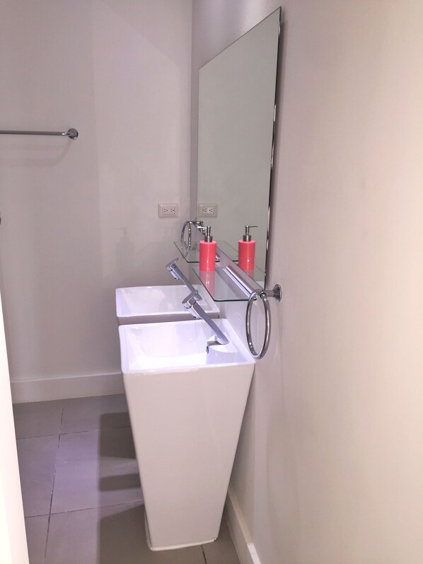Ein Badezimmer mit einem weißen Waschbecken, einem Spiegel und zwei roten Seifenspendern.
