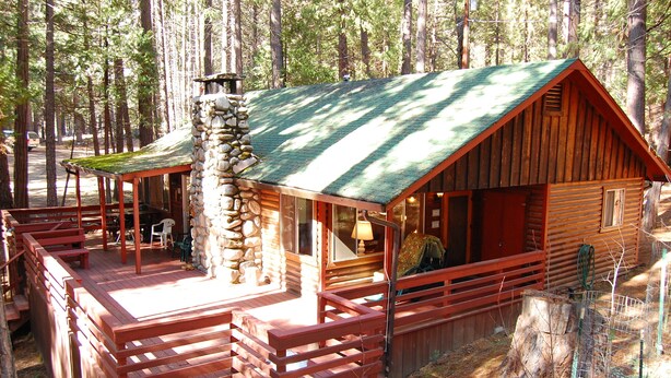A rustic cabin with a stone chimney, wooden deck, and a covered porch. - (28) Raccoon's End at The Redwoods In Yosemite (Yosemite National Park)