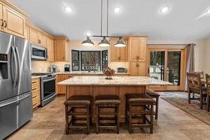 Une cuisine moderne avec des meubles en bois, des appareils en acier inoxydable et un îlot central doté de tabourets de bar.