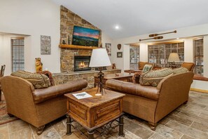 A cozy living room with leather sofas, a fireplace, and a stone wall.
