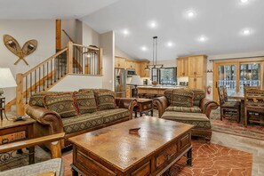 A spacious living room with a large wooden coffee table, two sofas, and a staircase leading to an upper level.