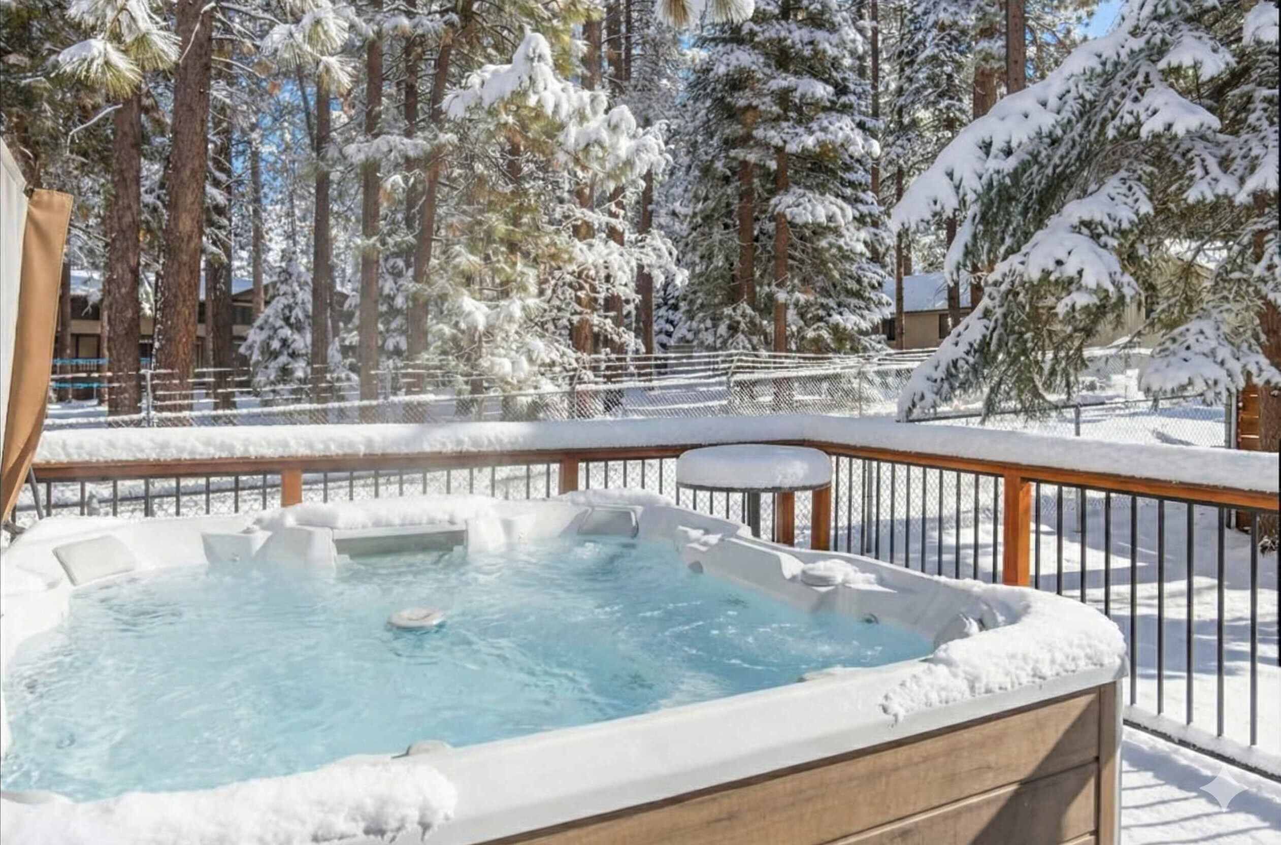 A hot tub surrounded by snow-covered trees and a wooden deck.