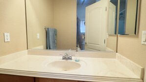 A bathroom with a large mirror, a sink, and a towel rack.