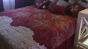 Ein Schlafzimmer mit Bett, Vorhängen, Nachttisch und weißem Kopfteil.