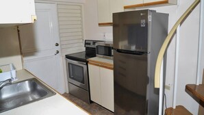Eine kompakte Küche mit einem Edelstahl-Kühlschrank, einer Mikrowelle, einem Backofen und einem Spülbecken.