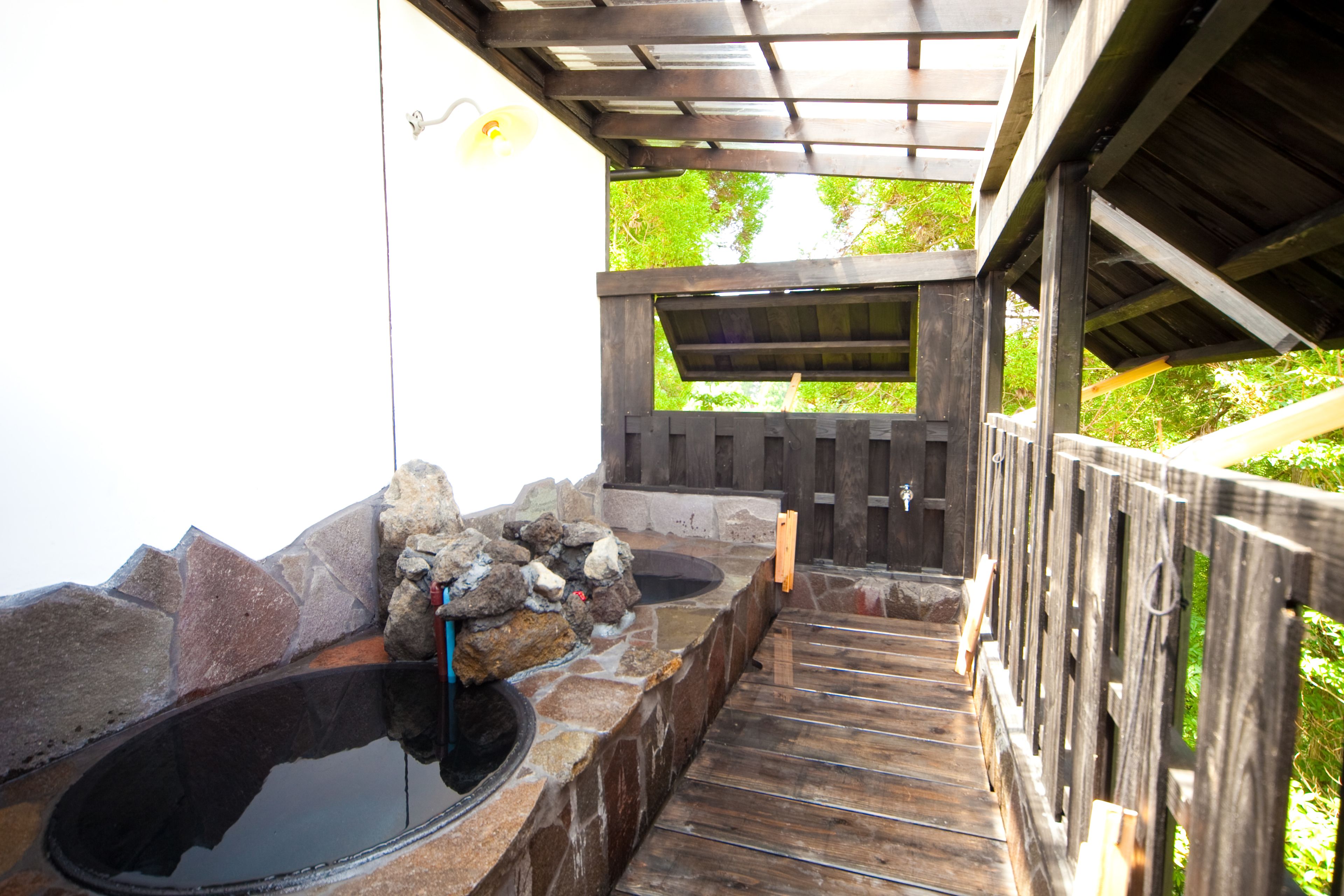 A stone hot tub area with a wooden deck and a wooden fence.