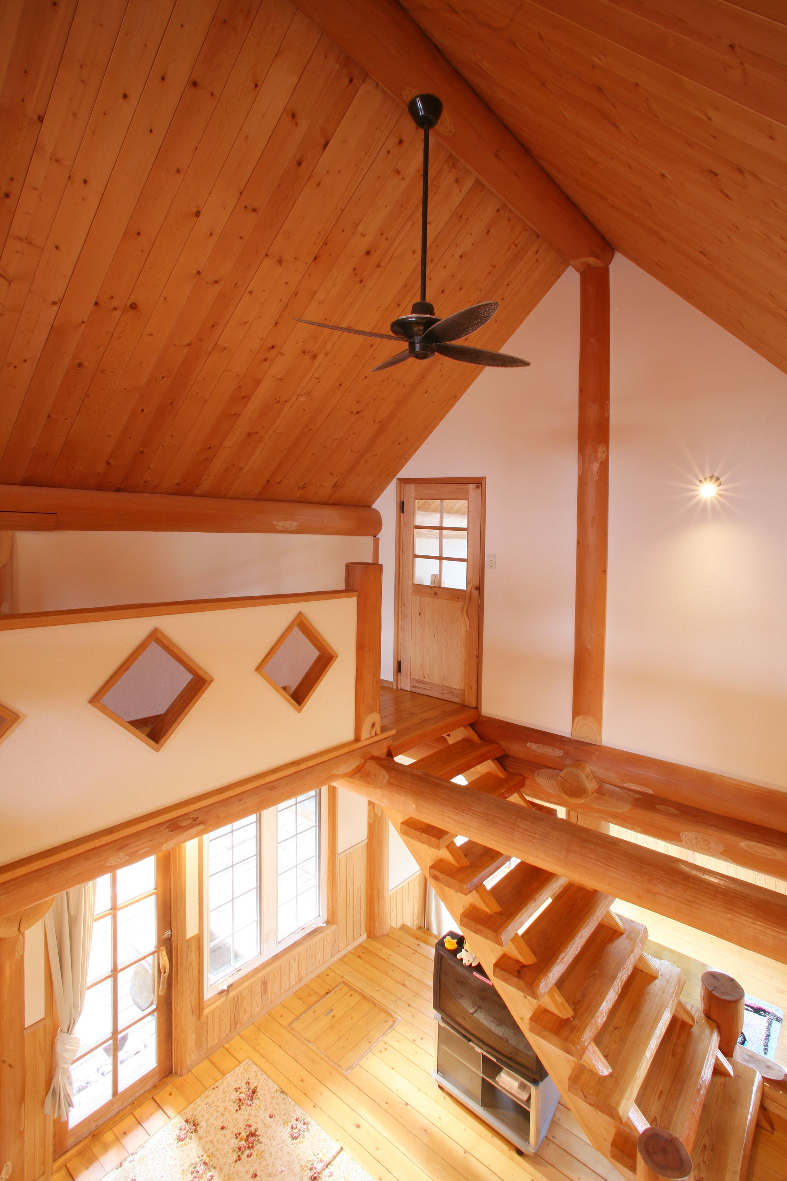 Un intérieur en bois avec un plafond en pente, un escalier et une cheminée.