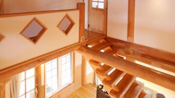 Un intérieur en bois avec un plafond en pente, un escalier et une cheminée.