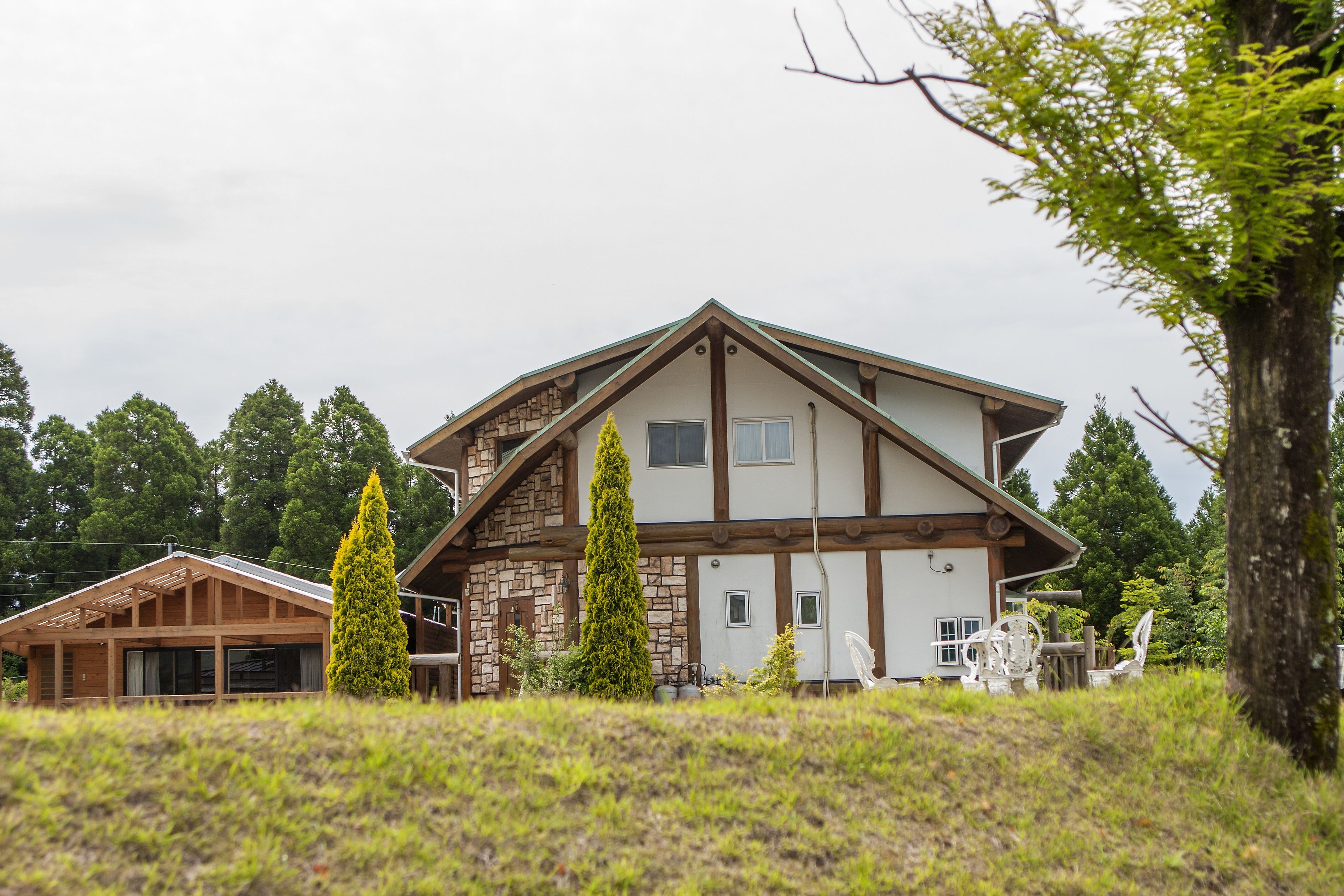 A large two-story house with a stone facade, wooden beams, and a sloped roof.