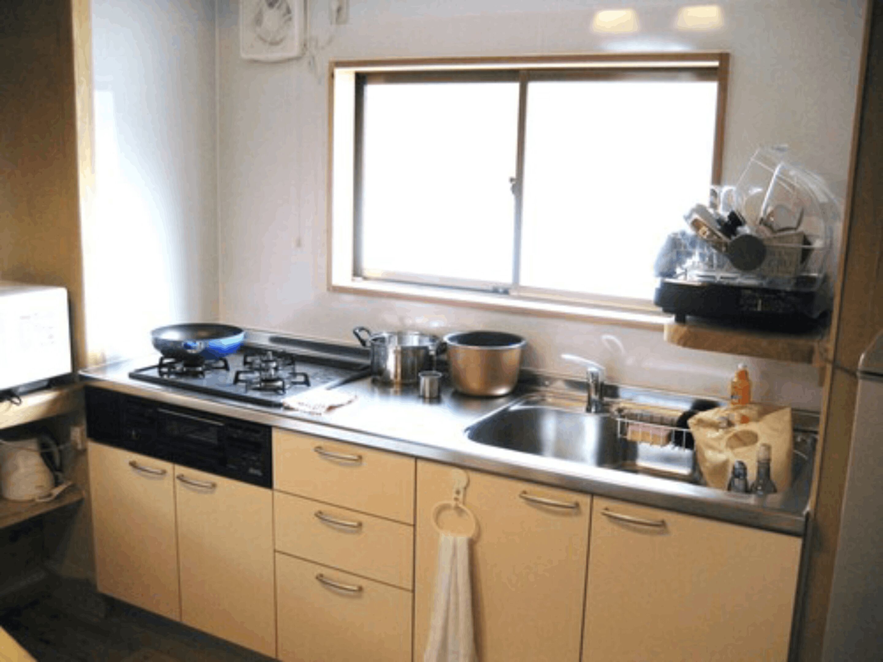 A compact kitchen with a gas stove, a sink, and a window above the countertop.