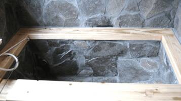 A stone-walled room with wooden beams and a metal ring.