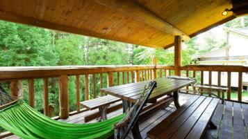 Relax in a serene outdoor space surrounded by lush greenery, featuring a hammock and picnic tables.