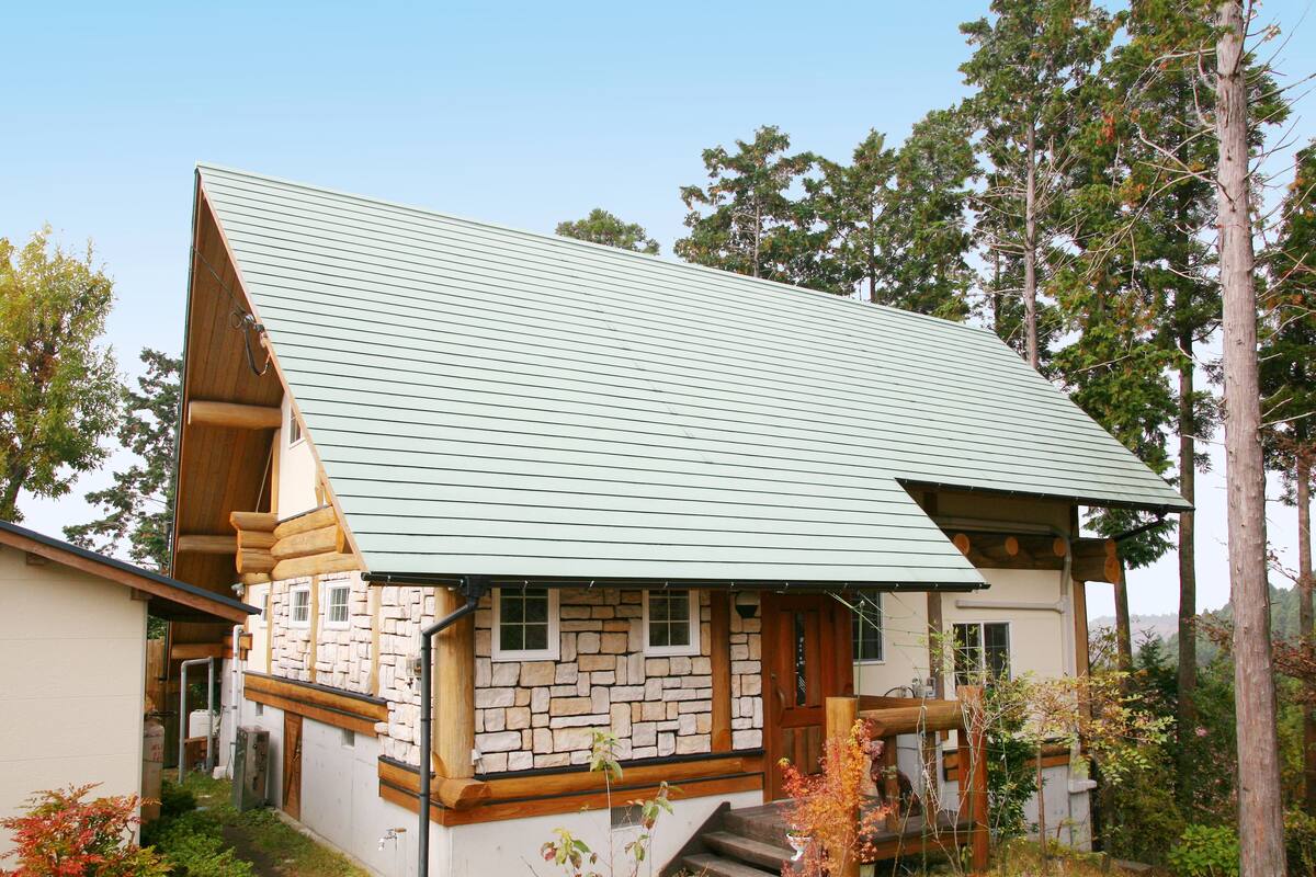A log cabin with a stone foundation, a sloped roof, and a wooden porch.