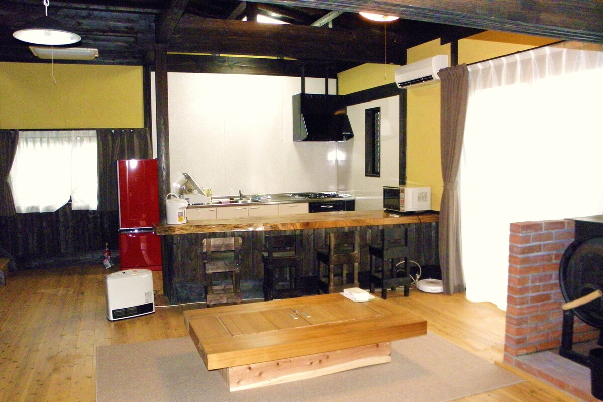 A compact kitchen with a wooden table, a refrigerator, a microwave, and a sink.