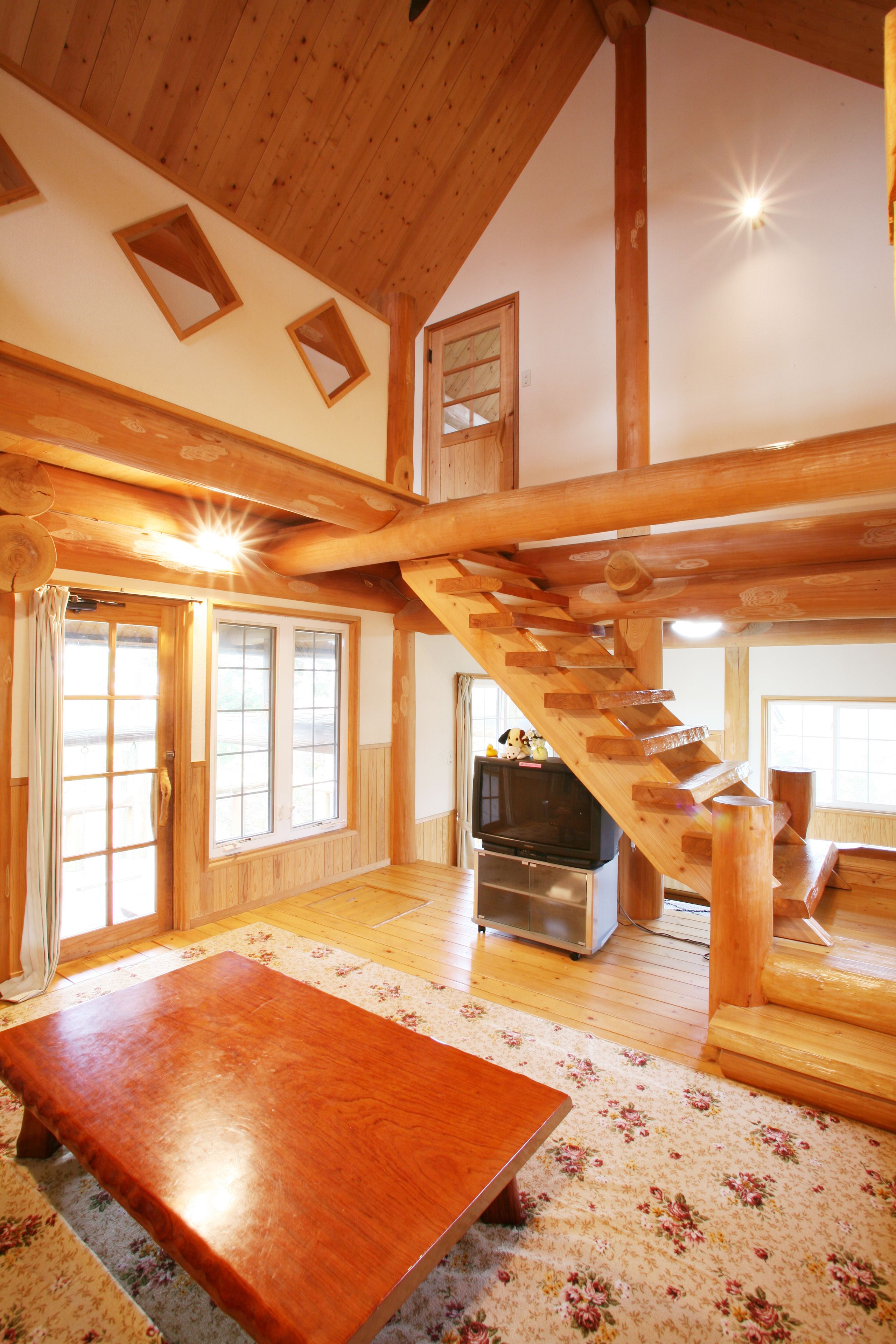 A spacious room with a wooden staircase, a television, and a dining table.