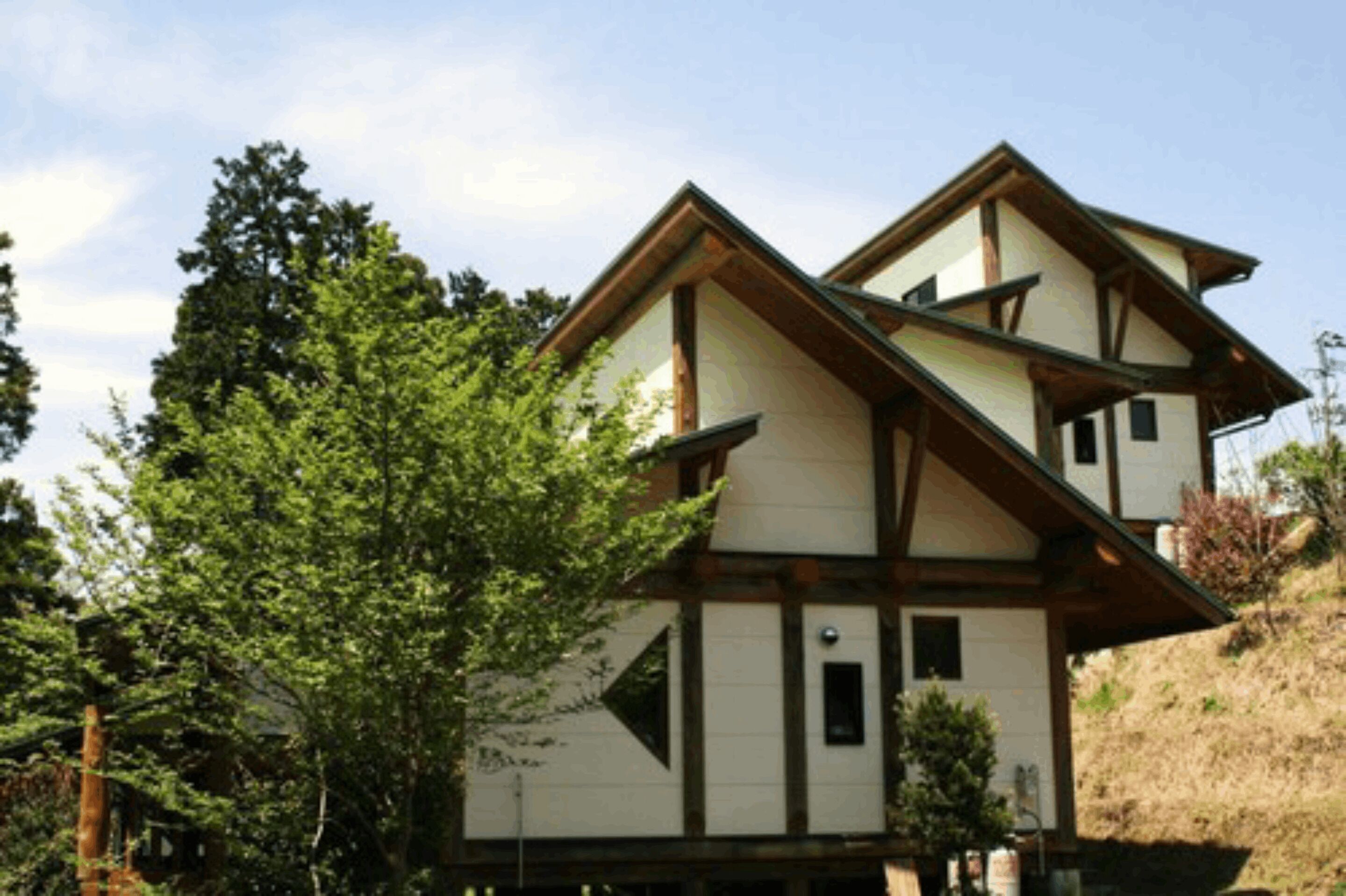 Un bâtiment à deux étages doté d’une façade symétrique, caractérisé par une combinaison d’éléments en bois blancs et bruns, et surmonté d’un toit à pente.