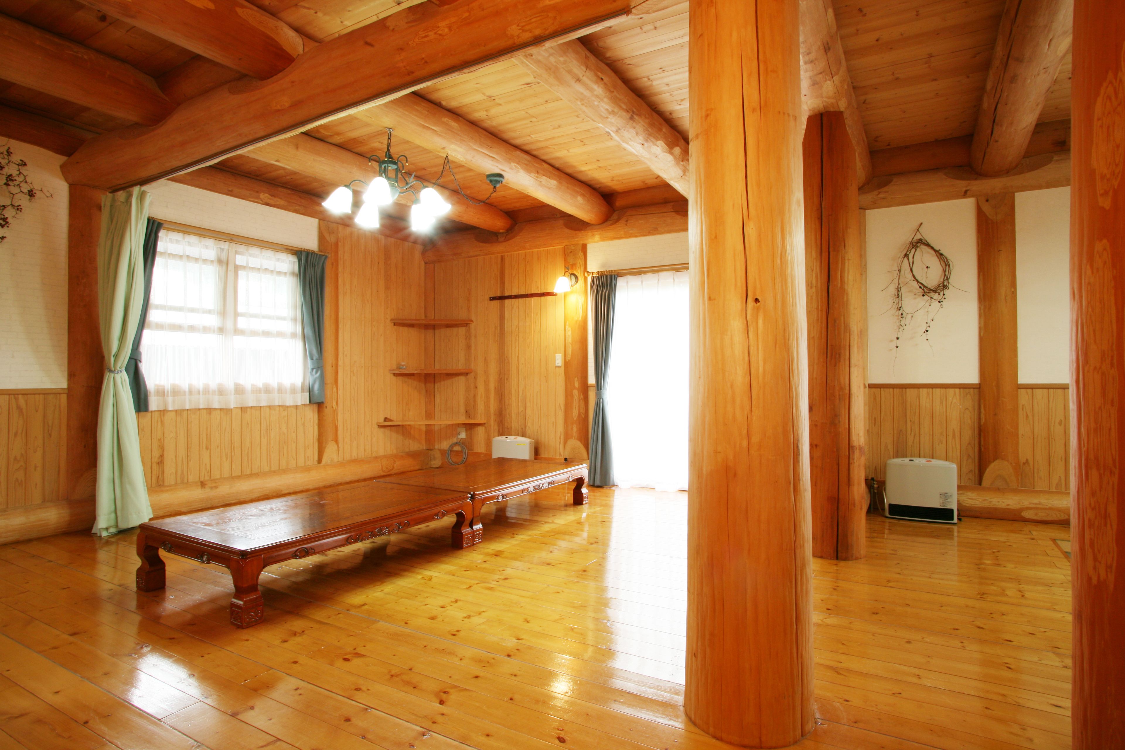Una habitación amplia con pisos de madera, un banco grande de madera y un techo con vigas a la vista.