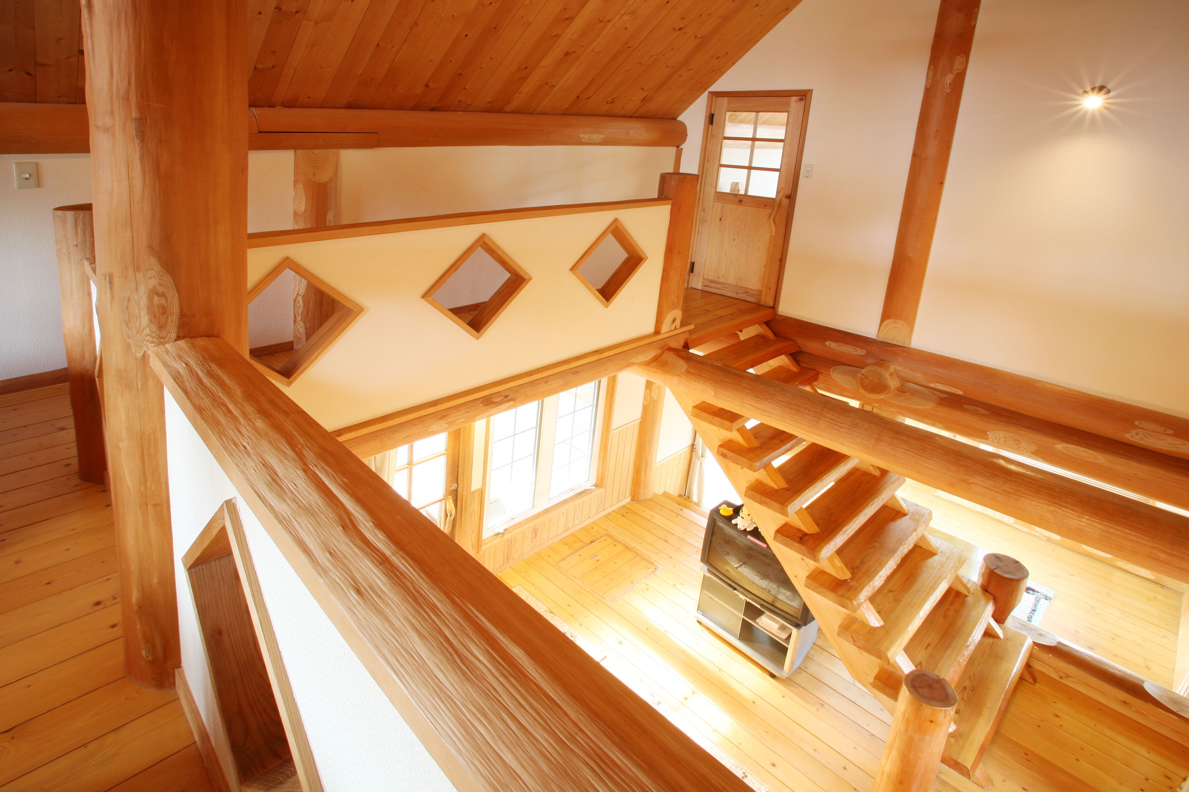 A wooden interior with a loft area, wooden beams, and a fireplace.