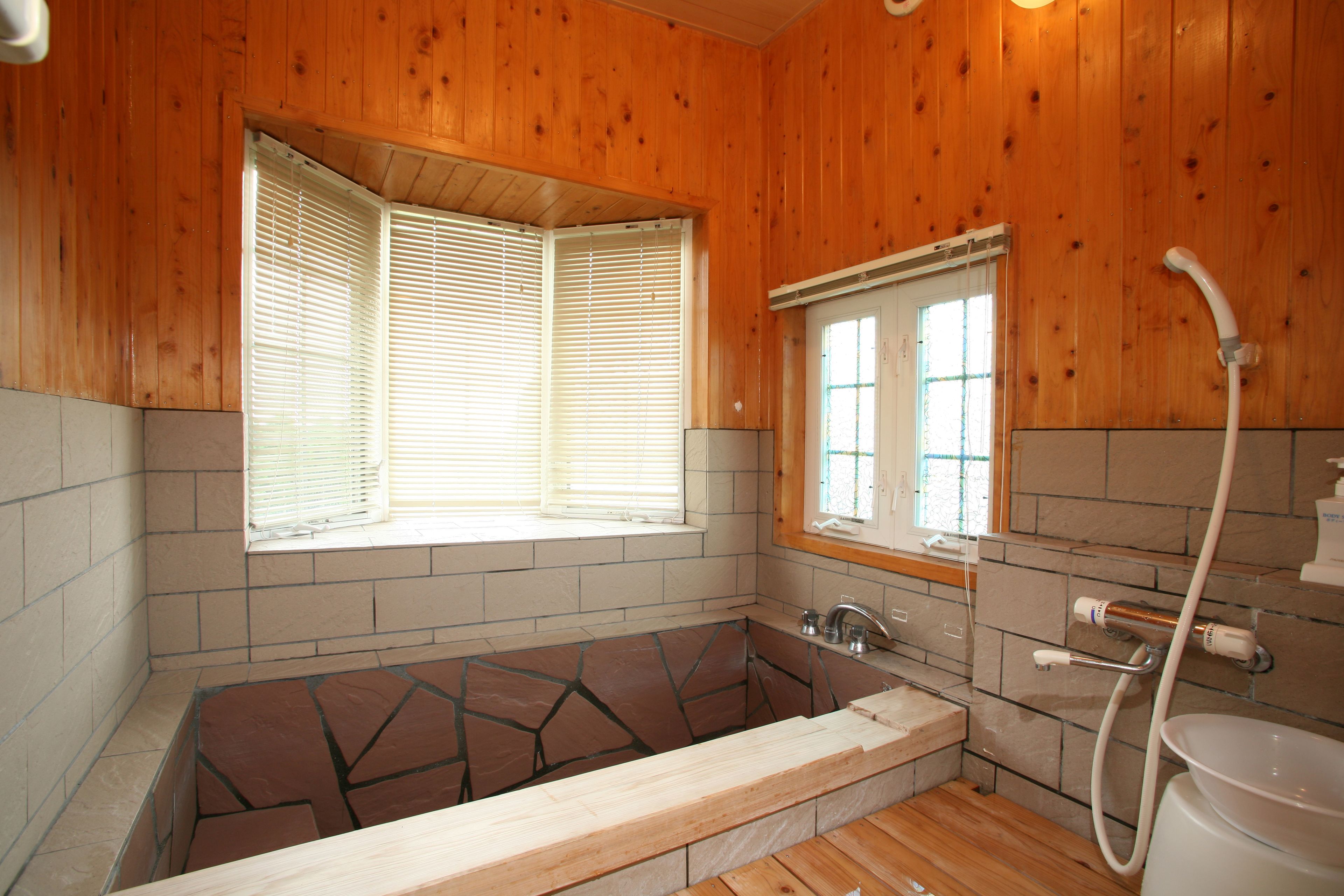 Une salle de bain rustique, avec une cabine en bois, une baignoire, une fenêtre et une douche.