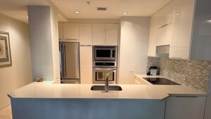 A modern kitchen with a central island, stainless steel appliances, and a tiled backsplash. - Old Town Scottsdale - Optima Camelview - Modern/Furnished, Walk To All Amenities (Scottsdale)