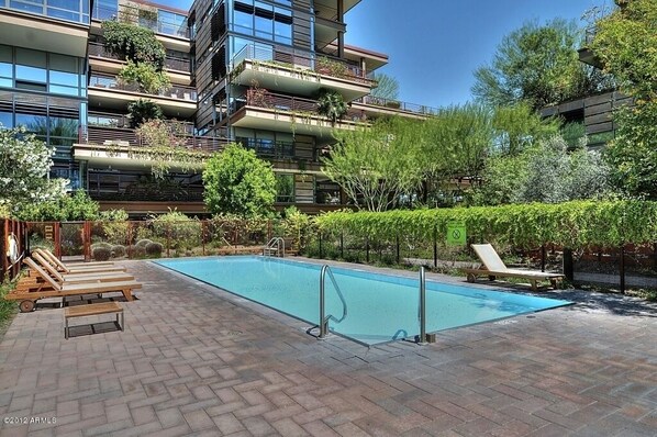 A modern apartment building with a rooftop garden, a swimming pool, and outdoor seating.