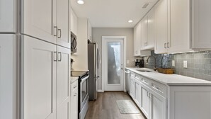 A modern kitchen with white cabinetry, a stainless steel refrigerator, and a tiled backsplash.