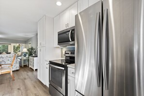 Una cocina moderna con electrodomésticos de acero inoxidable, armarios blancos y una zona de comedor de madera.