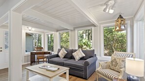 A spacious living room with a large window, a sofa, a coffee table, and a lamp.
