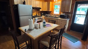 L’intérieur d’un chalet en bois comprend un coin cuisine, une table à manger, des chaises et une fenêtre.
