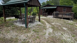 Un chalet rustique doté d’une véranda et d’une table de pique-nique couverte.