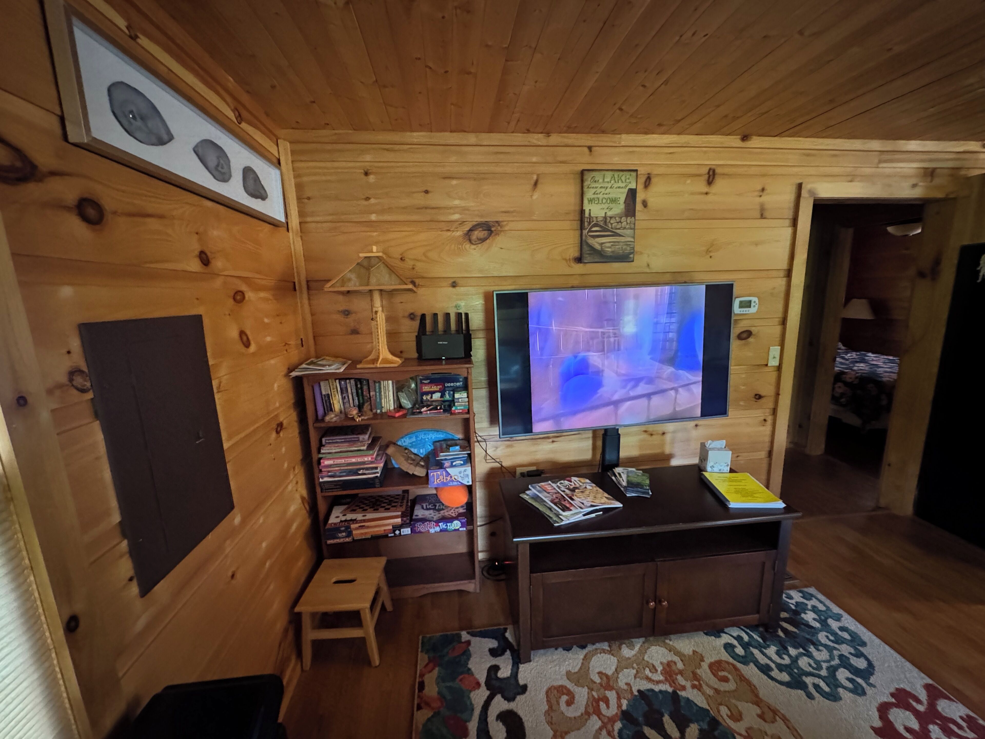 Una stanza con pannelli in legno, una televisione, scaffali, un tavolino e un tappeto decorato.