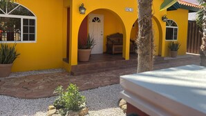 A yellow building with a sign reading "OPAL 84" and a wooden bench outside. - Casa Opal vacation home, 5 min from the beach! (Noord)